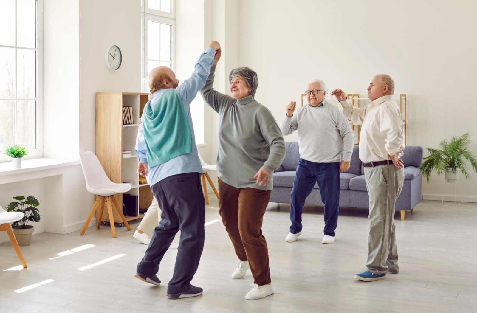 Seniors at a memory care community enjoying dancing together during music therapy