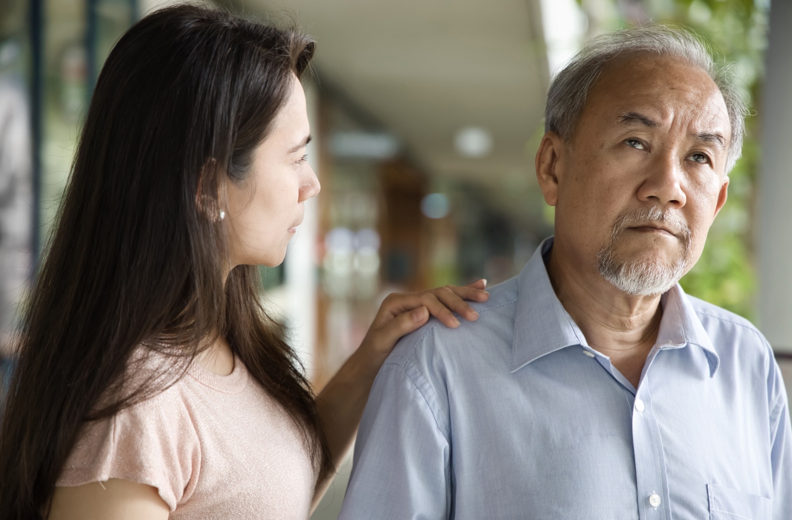 A daughter looking concerned while supporting her parent with Alzheimer’s disease.